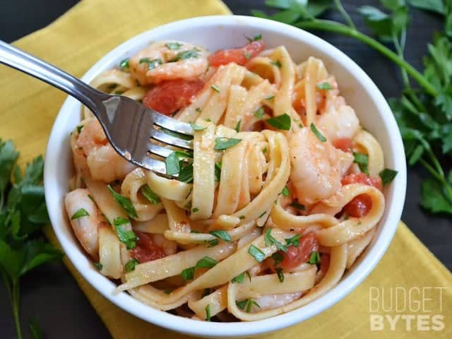 It takes less than 30 minutes to make this super flavorful and filling Spicy Shrimp Tomato Pasta. Dinner made FAST! BudgetBytes.com fork Top view of a bowl of spicy shrimp tomato pasta in bowl with fork