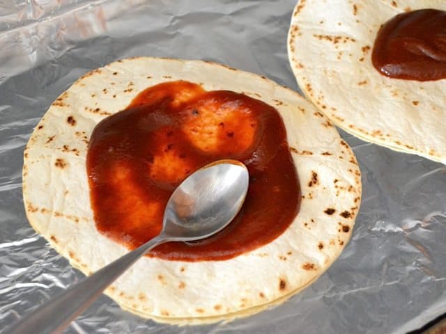 BBQ sauce spread on tortillas with spoon