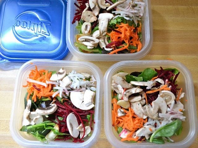 Salad divided into three different Tupperware containers