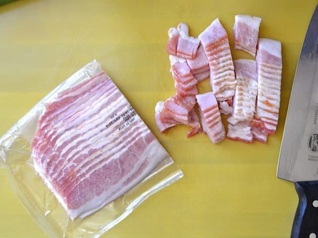 Bacon being chopped up with knife on cutting board