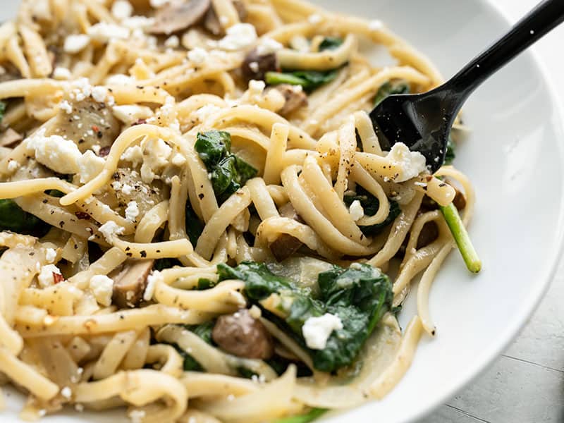 Close up of Spinach and Artichoke One Pot Pasta on the plate being twirled around a fork