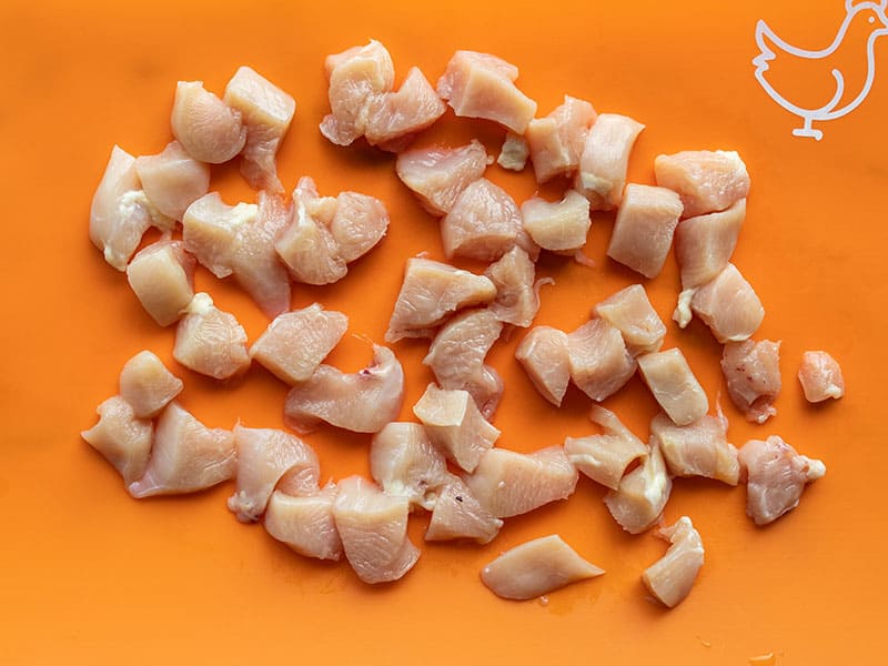 Diced chicken breast on an orange cutting board