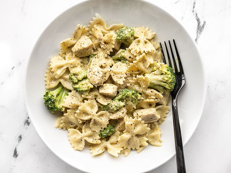 A super fast creamy pesto sauce drenches tender pasta, chicken breast, and broccoli for an easy weeknight dinner. Budgetbytes.com A bowl full of creamy pesto pasta with chicken and broccoli, a black fork on the side