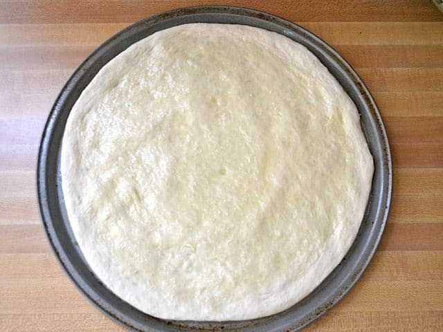 Oiled and rolled dough shaped into circle and placed on pizza pan