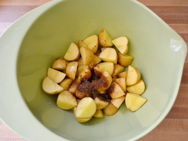 Chopped potatoes and seasoning added to mixing bowl