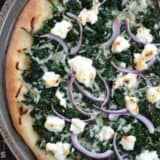 A close-up of spinach pizza with melted cheese.