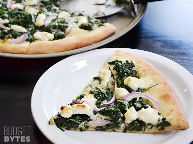 Close up of a slice of Easy White Spinach Pizza on a white plate
