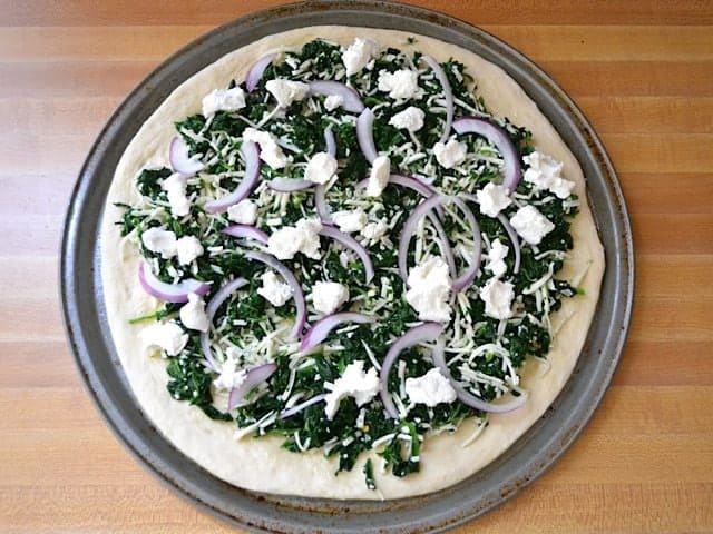 Pizza toppings added to crust, spinach mixture, red onion and goat cheese