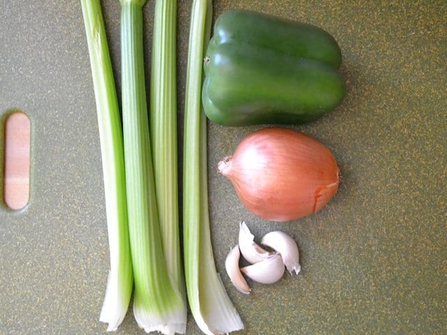 Celery, green bell pepper, onion and garlic on cutting board