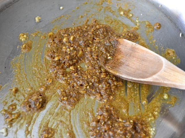 Curry Powder added to garlic and onion in skillet, mixed with wooden spoon