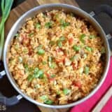 A pot of chorizo chicken jambalaya garnished with herbs.