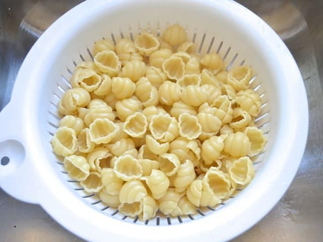 Cooked pasta in colander to drain