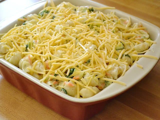 Pasta mixture poured into casserole dish and shredded gouda sprinkled over the top