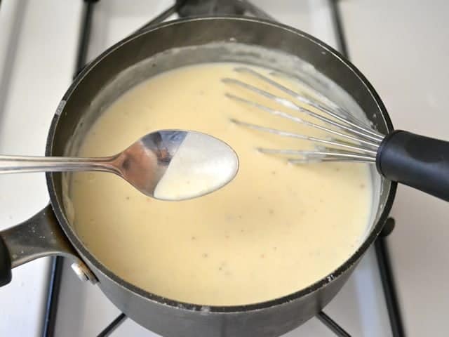 Parmesan cheese added to sauce mixture in pot