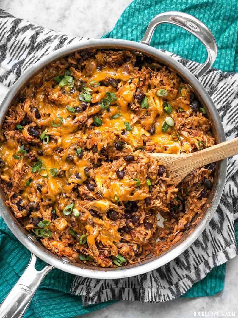 If you're looking for a quick and easy dinner, this Southwest Chicken Skillet is it! Precooked chicken makes this dinner possible in about 30 minutes. BudgetBytes.com top view of southwest chicken skillet with wooden spoon