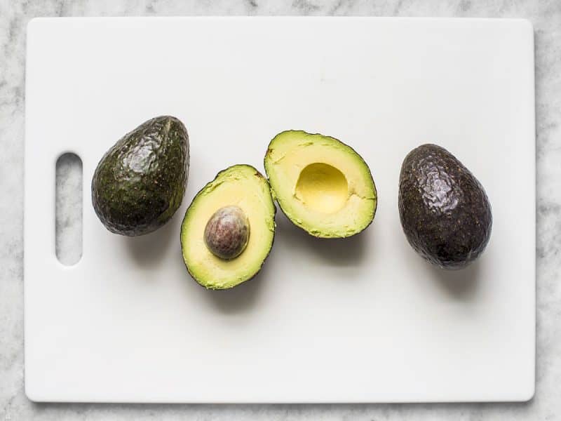 Three avocados, one cut in half
