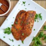 Blackened tilapia served on a plate with coriander.