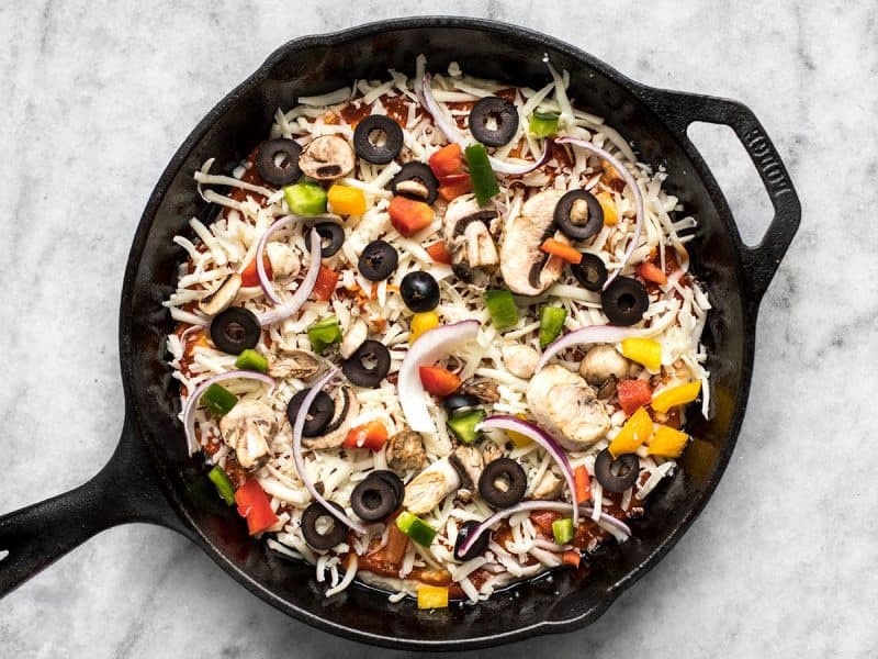 Cheese and toppings put on top of dough and ready to bake