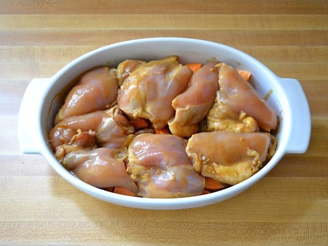 Marinated raw Chicken Thighs placed over cubed sweet potatoes in casserole dish