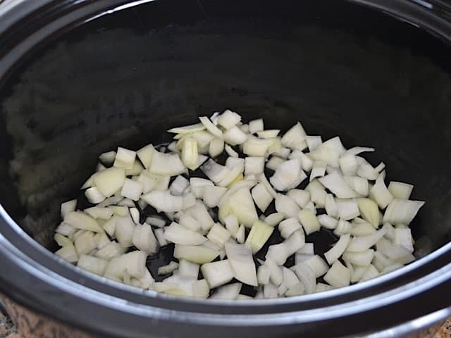 Diced onion and wine in bottom of slow cooker