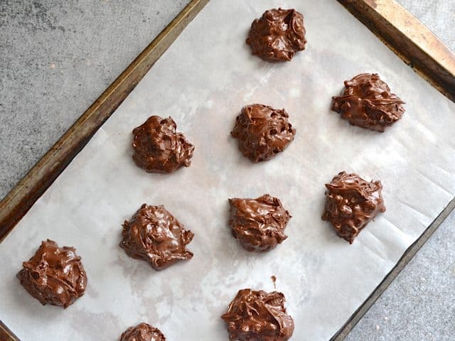 Cookie sheet lined with parchment paper with unbaked cookie dollops placed on top