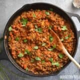 A bowl of curried lentils garnished with herbs.
