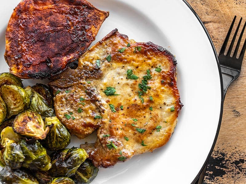 Honey Mustard Pork Chops are anything but boring with a sweet, tangy, and savory homemade honey mustard glaze. Budgetbytes.com Honey mustard pork chop on a plate with brussels sprouts and sweet potato