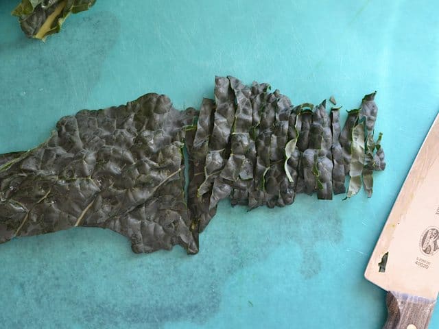 Chopping kale with knife on cutting board