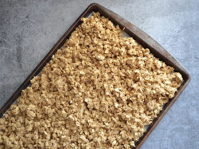 Granola spread out on baking sheet ready to bake