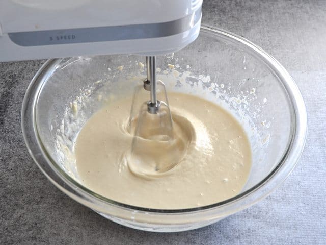 Bread dough mixture being mixed in mixing bowl with hand mixer