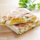 Stacked green chile breakfast quesadillas on a wooden surface.