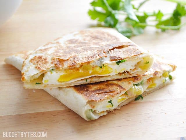 Two slices of Green Chile Breakfast Quesadilla with cilantro on the side