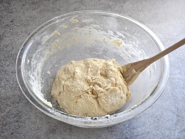 Flour being added to dough ball in mixing bowl