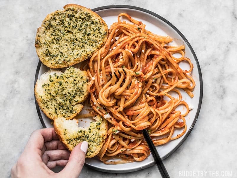 Make your own homemade freezer garlic bread slices, ready to bake on demand. Bake two or ten frozen slices at a time, ready in minutes! Budgetbytes.com Two slices of homemade freezer garlic bread on a plate with pasta and red sauce