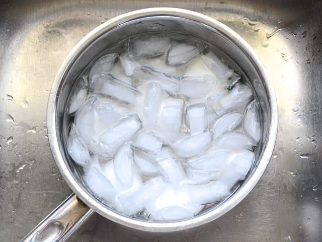 Ice cubes placed in pot of water and eggs to stop cooking (ice bath)