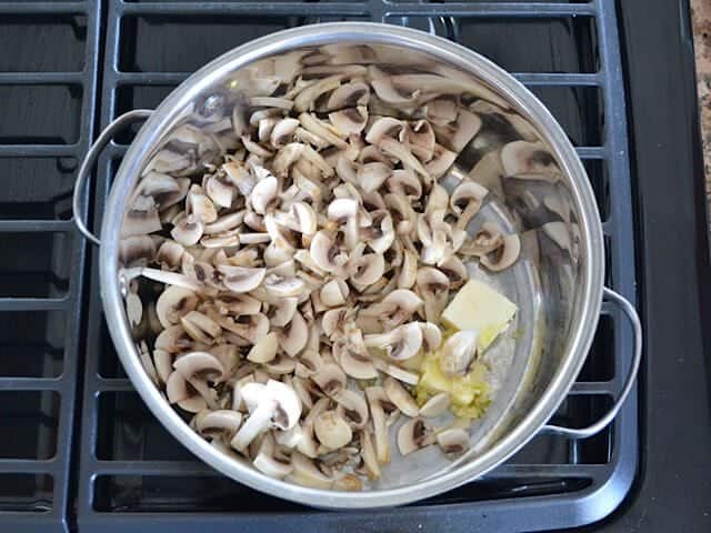 Sliced mushrooms, garlic and butter in pot on stove top