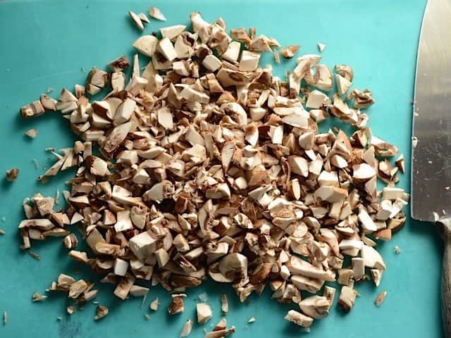 Chopping Mushrooms with knife on cutting board