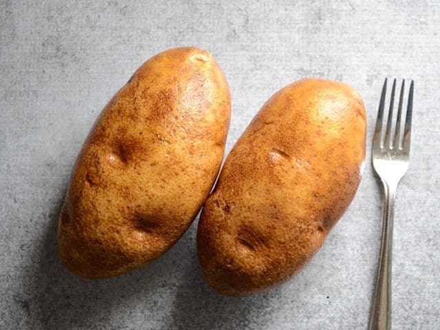 Two russet potatoes with a fork