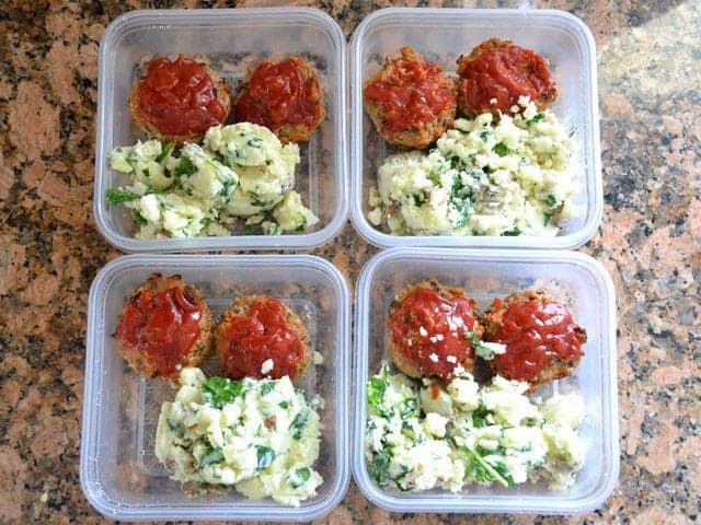 Meat loaves and potatoes portioned out into four Tupperware dishes to freeze for later