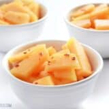 Bowls of chili lime cantaloupe garnished with herbs.