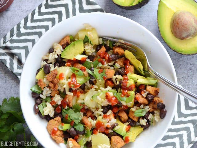 Top view of a Sweet n Spicy Chicken Bowl topped with Siracha, sitting on a gray and white chevron napkin