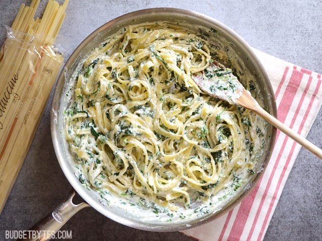 This quick and luxurious Spinach Ricotta Pasta boasts a creamy and garlicky spinach sauce made easy with ricotta cheese. BudgetBytes.com skillet Overhead view of a skillet full of spinach ricotta pasta on a red and white striped napkin