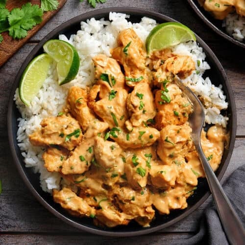 Overhead view of thai peanut chicken on a plate with white rice and lime rice.