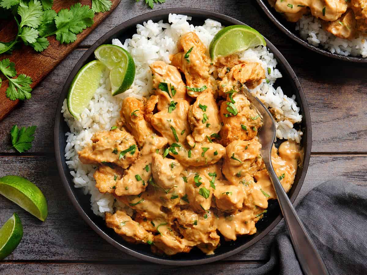 Overhead view of thai peanut chicken on a plate with white rice and lime rice.