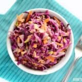 A bowl of apple cabbage slaw with fresh ingredients.