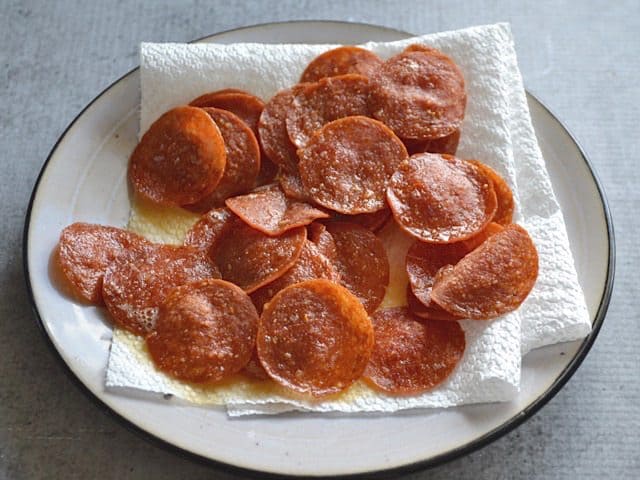 Draining pepperoni on a paper towel