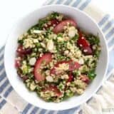 A colorful plum salad garnished with nuts and herbs.