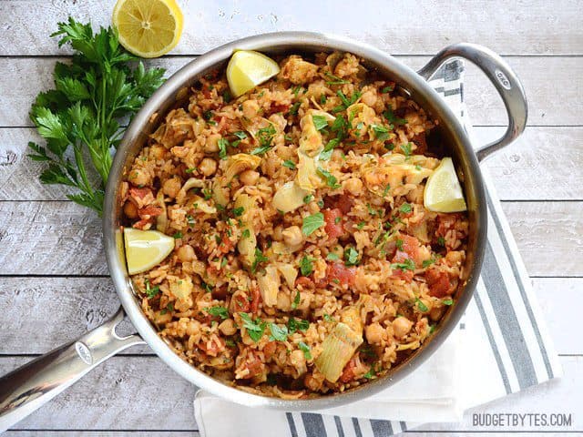 This one pot Spanish Chickpeas and rice has big flavor thanks to liberal dose of spices, artichoke hearts, and fresh lemon. Budgetbytes.com The finished skillet full of Spanish Chickpeas and Rice with lemon wedges and parsley