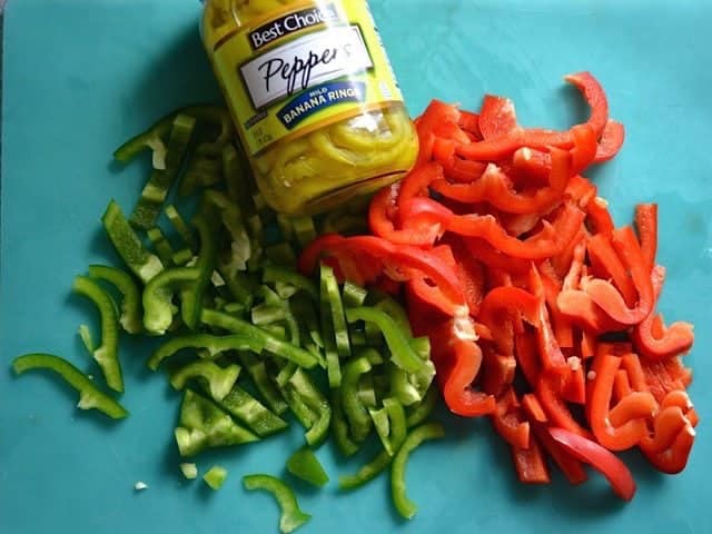Sliced green and red bell peppers and a jar of banana peppers