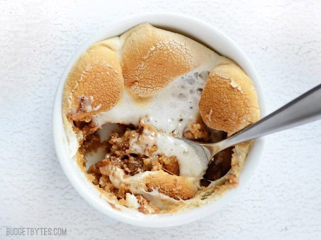 Get your favorite gooey s'mores flavors in a layered, oven baked S'mores Pot. Graham cracker crust, peanut butter, chocolate chips, and toasted marshmallows. Budetbytes.com Close up of one Peanut Butter S'mores Pots with a spoon digging in